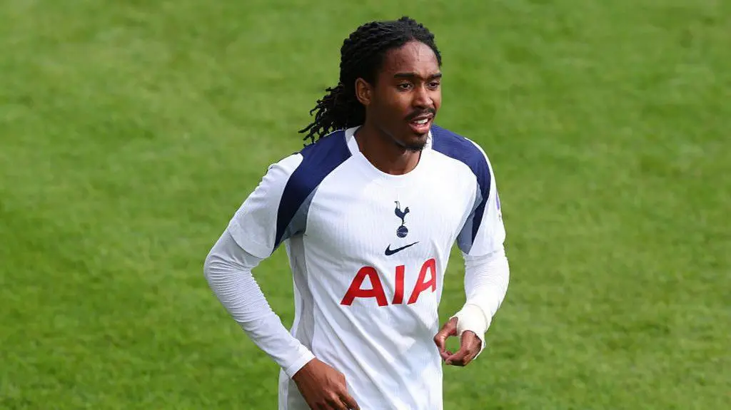 Djed Spence wearing a white Tottenham Hotspur kit on a green football pitch