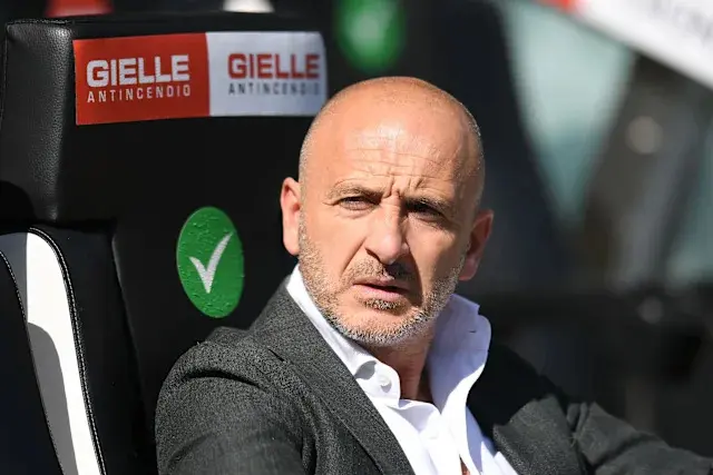 Piero Ausilio seated on the bench during a football match, focused expression.