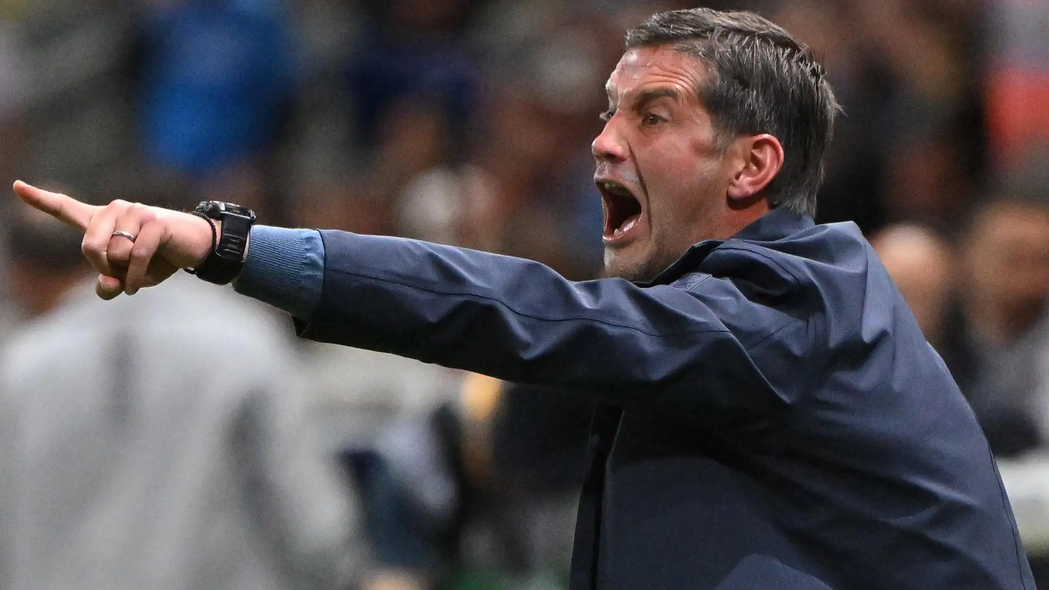 Cristian Chivu shouting and pointing during a match while wearing a dark blue jacket