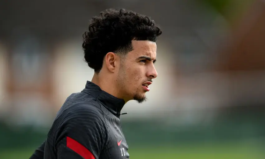 Side profile of Curtis Jones wearing a black Liverpool FC training top with red detailing.