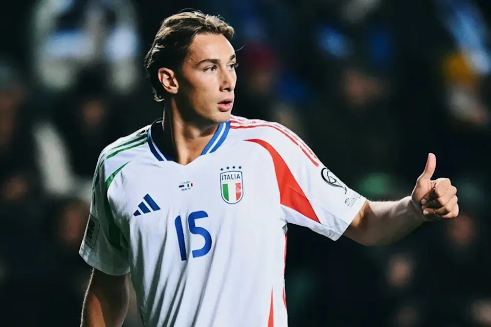 Pio Esposito wearing the white Italy national football team jersey with number 15, giving a thumbs up.