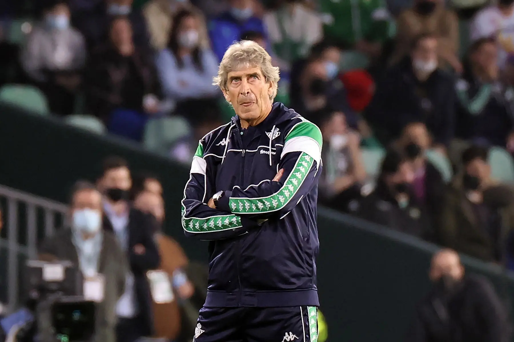 Manuel Pellegrini standing on the sidelines wearing a Real Betis training jacket with arms crossed