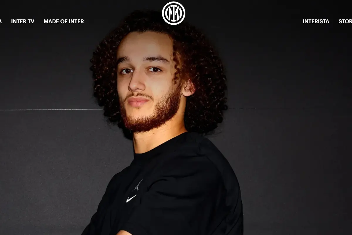 Portrait of Yanis Massolin wearing a black Nike shirt against a dark Inter Milan branded backdrop