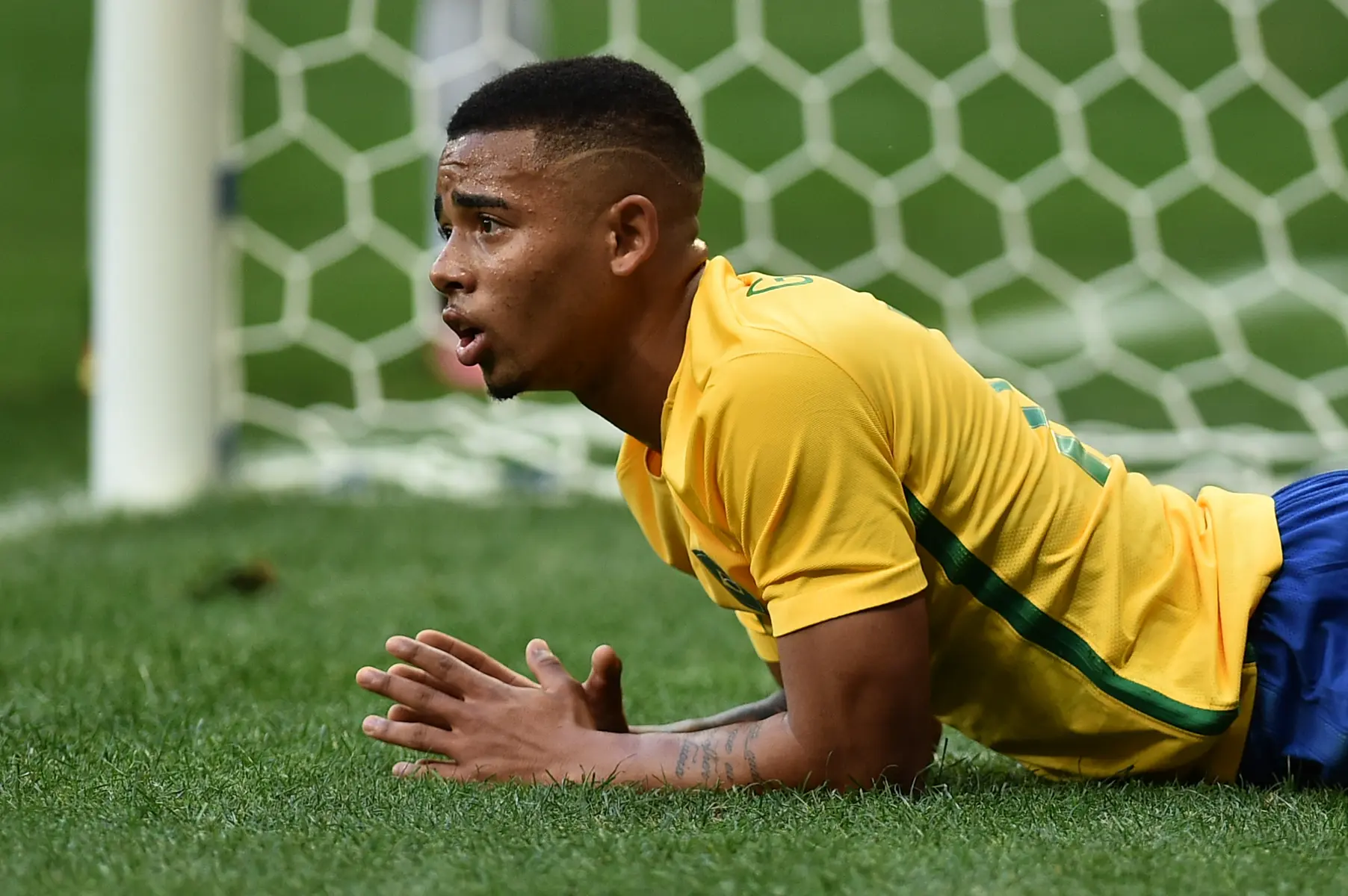 Gabriel Jesus lying on the grass in a yellow Brazil national team jersey