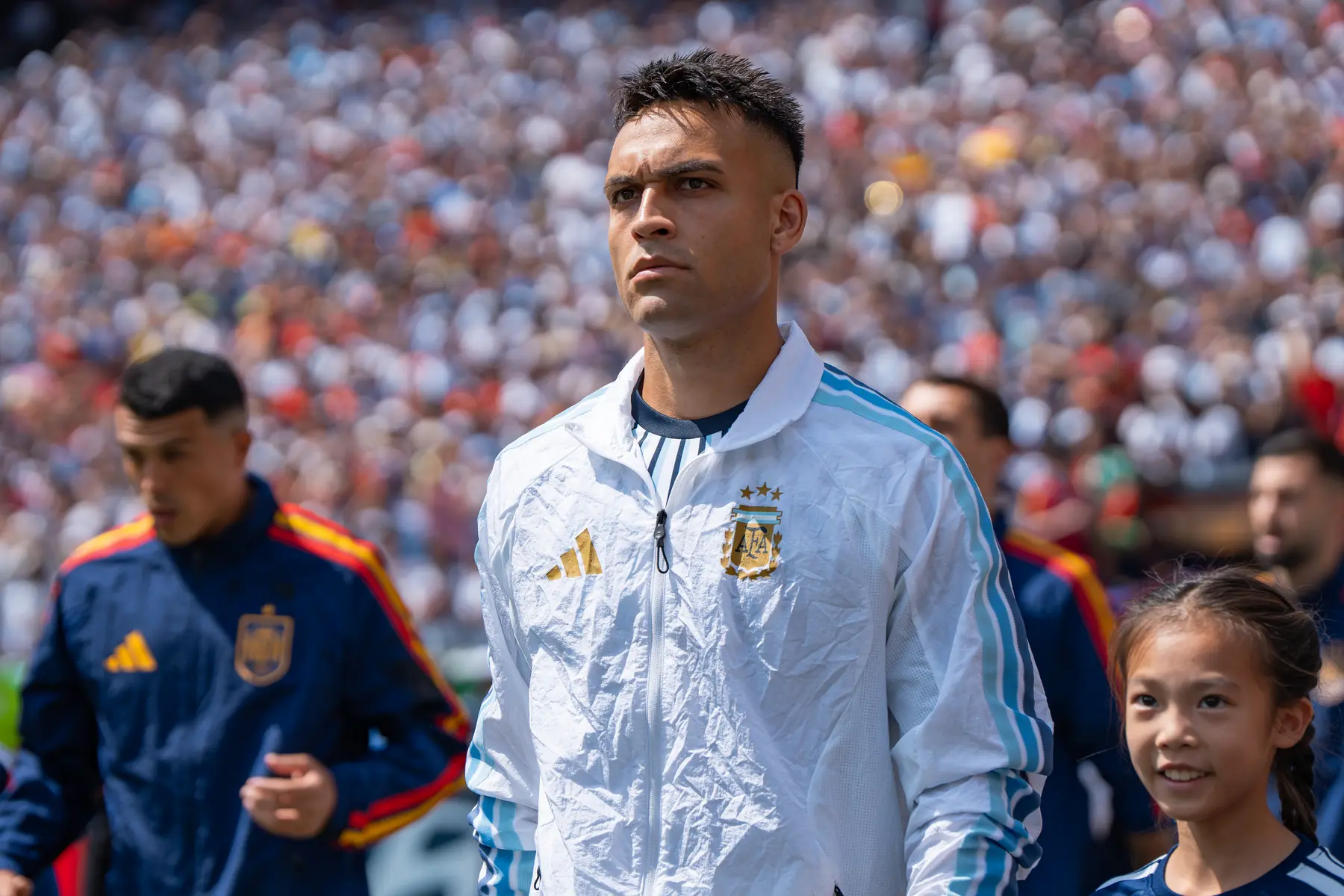 Lautaro Martinez wearing a white Argentina national team jacket during a match against Spain.